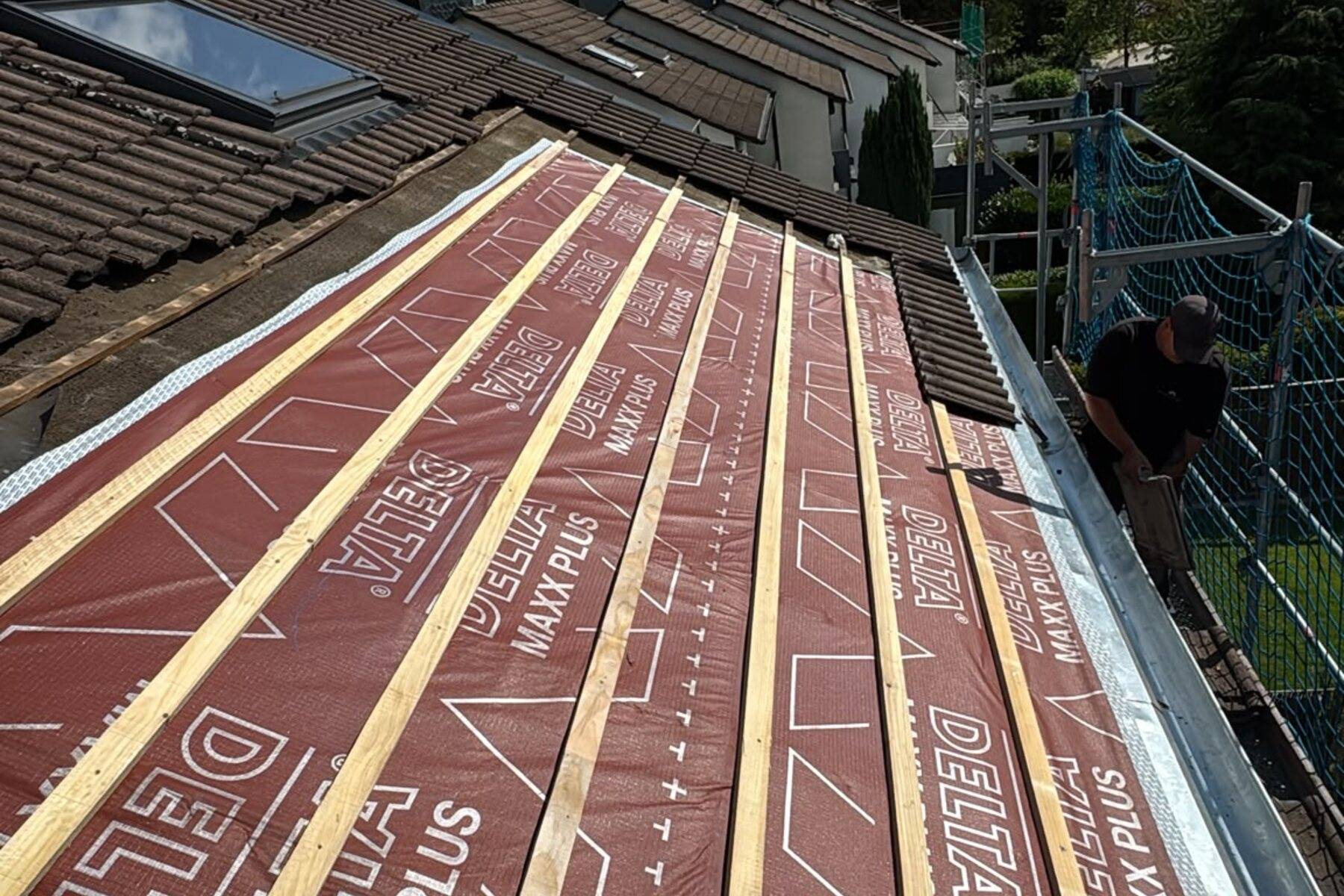 Dachfläche von oben: Dachlatten und Konterlatten über einer roten Unterspannbahn