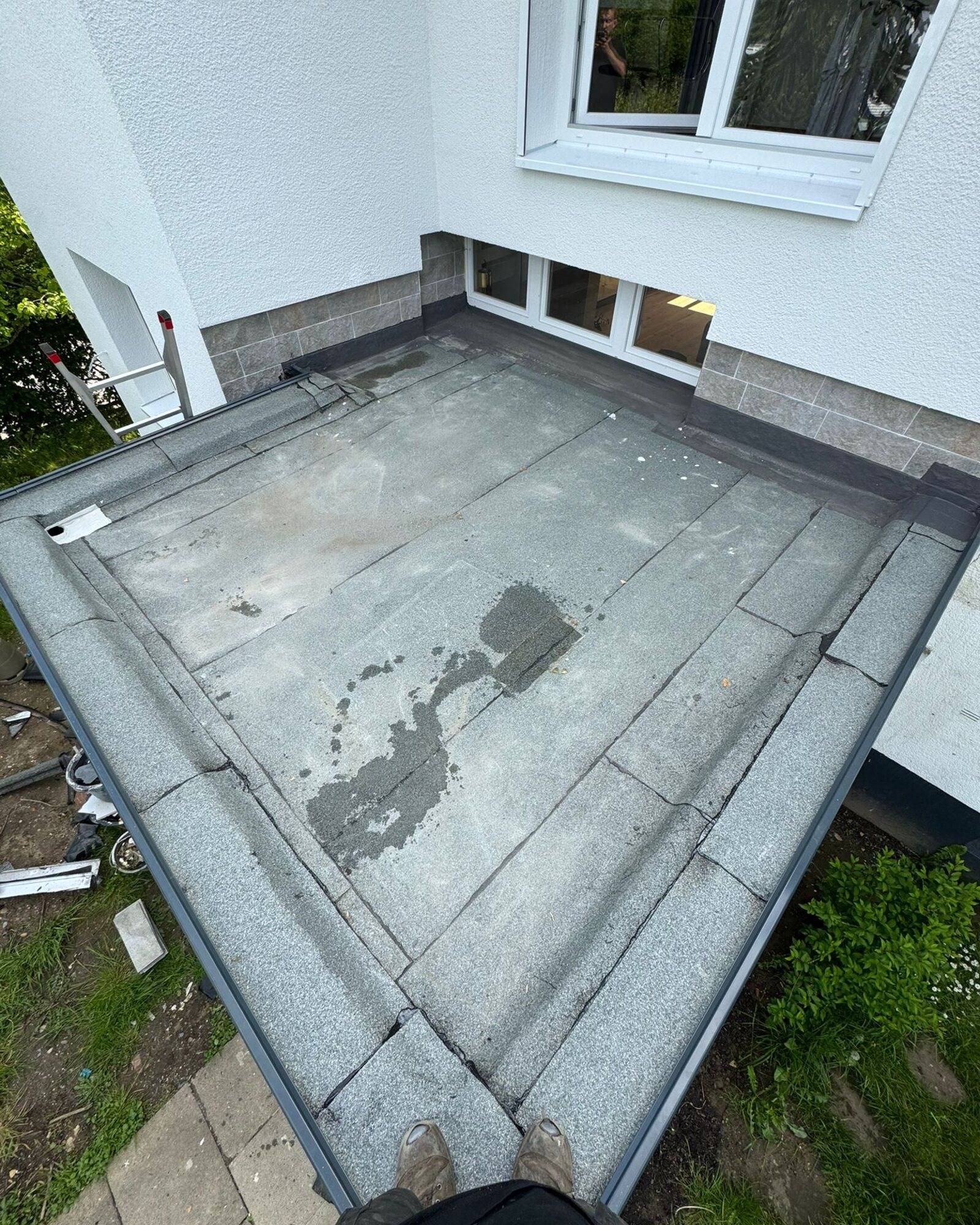 Flachdach mit feuchten Stellen auf der Abdichtung an der Hauswand