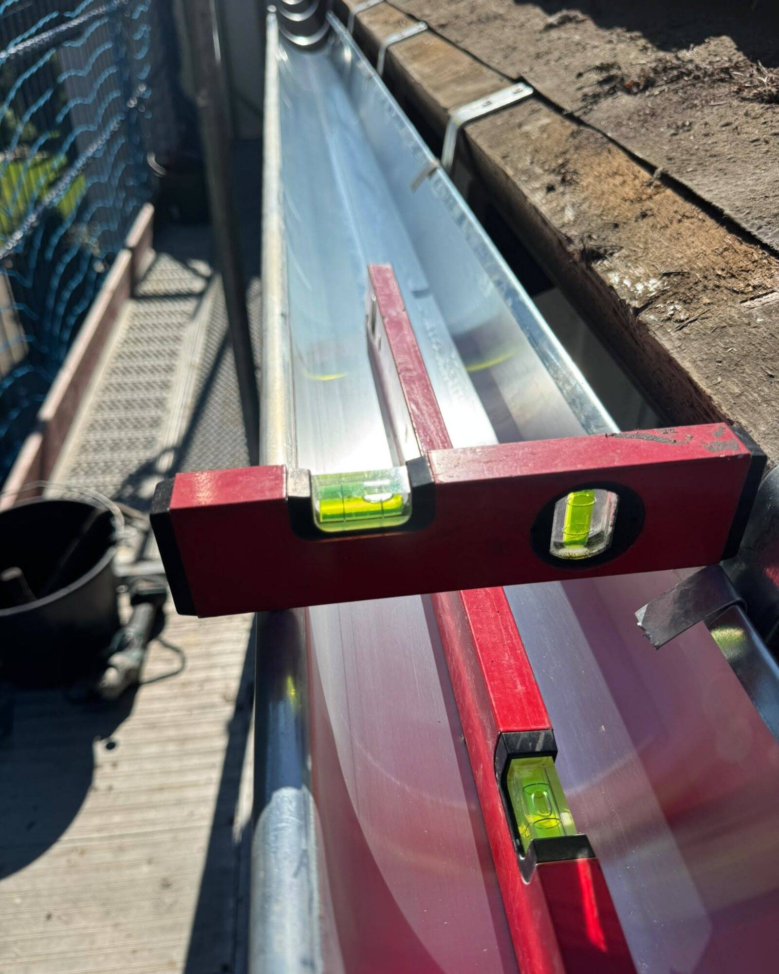 Dachrinne aus Zink, die mit einer Wasserwaage auf ihr Gefälle geprüft wird