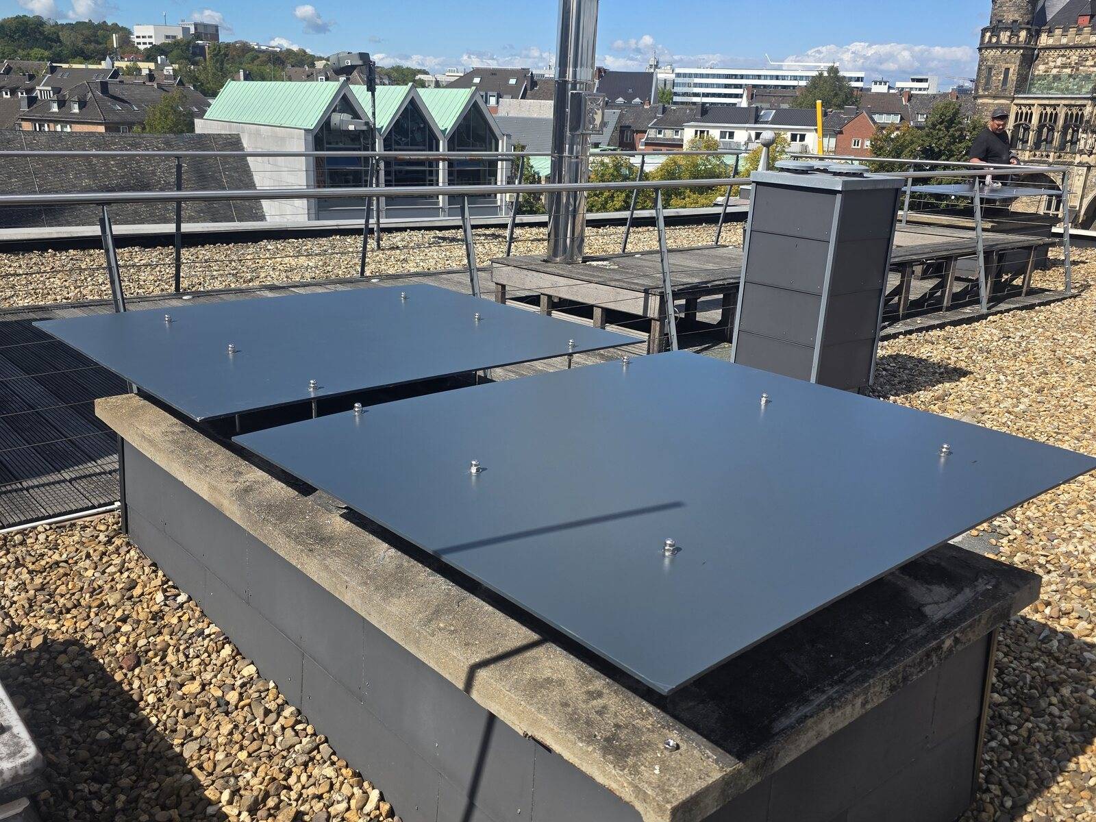 Flachdach mit dunklen Abdeckplatten und Blick über die Stadt